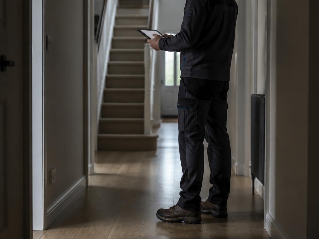 Tradesperson reviewing job details on a tablet inside a residential property